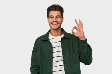 Young handsome caucasian man isolated on white background cheerful and confident showing ok gesture.