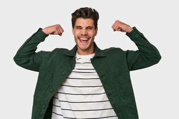 Young handsome caucasian man isolated on white background showing strength gesture with arms,...
