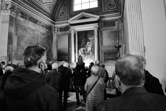 People  watching a painting  whilst visiting a church in Rome, Italy