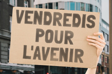 The phrase " Friday For Future " is drawn on a carton banner in a woman's hand. Infection. Destruction. Damage. Bad. Poison. Toxin. Poisoning. Harm. Air. Contamination. Emission. Quality. Zone