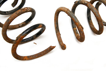 The old rusty broken coiled spring from the car suspension isolated in a white background.