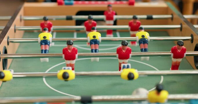 Close-up of foosball players figurines trying to kick ball . People play mini foosball and score a goal with a ball into the goal.slow motion