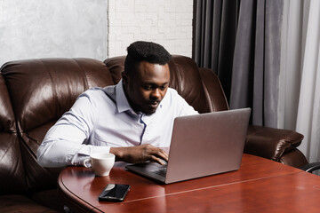 African american IT developer with laptop is programming code in office. African business man...