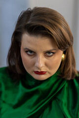 Fototapeta premium Portrait of attractive beautiful fashionable plus size young woman dressed in the style of 1980s, with bright fancy make up, red nails, glasses, green silk shirt. 80s inspiration and vibes