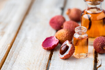 Glass bottles with pure organic essential litchi oil on wooden background. Concept of natural ingredients for beauty treatment, skin care, massage. Exotic fruit extract