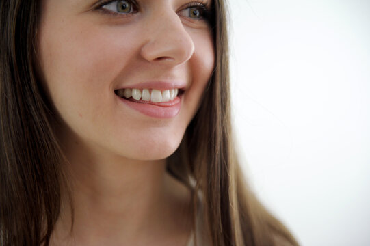 close-up happy girl's face teeth clean white even smile sincere laughter on a white background close-up frame nice young woman is looking up over white background. High quality photo