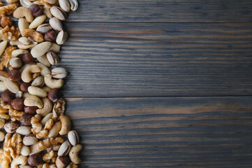 mixed nuts in a bowl on wooden table, top view with copy space.