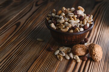 mixed nuts in a bowl on wooden table, top view with copy space.