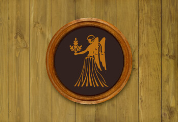 The sign of the zodiac Virgo in a round frame on the wall of the boards