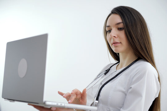 Young female doctor looking away while using laptop at desk in clinic. High quality photo