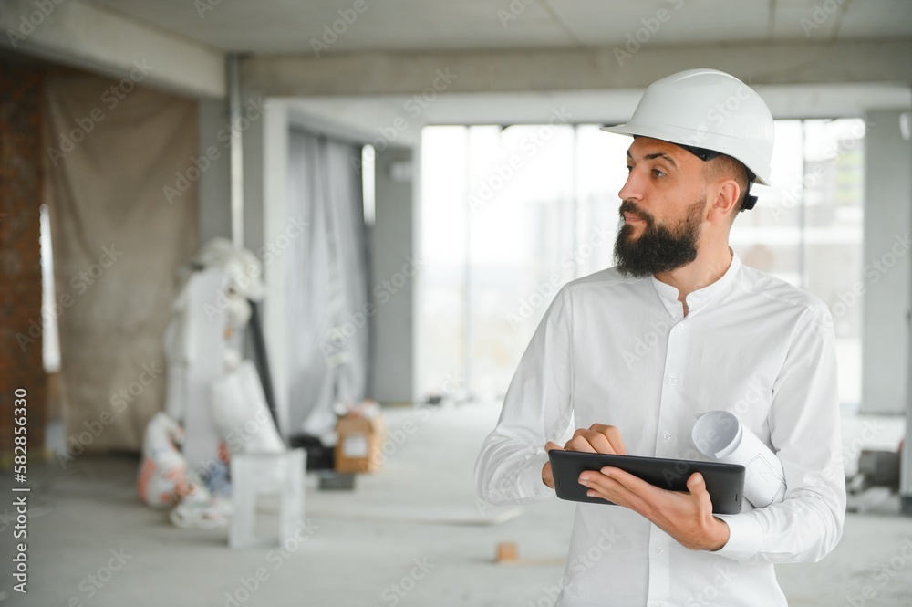 Wall mural Young attractive arabic industrial engineer in hard hat. Professional and industry, builder architect job, worker checking work at plant indoor