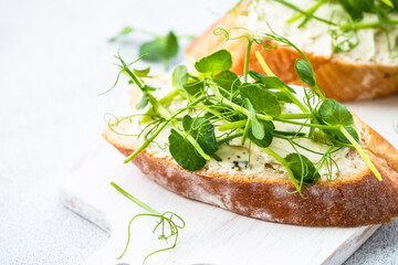 Toast with micro greens, green pea and cream cheese at blue. Healthy food snack, vegetarian. Close up.