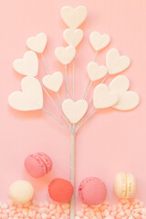 Heart shaped tree dessert in flat lay design with premium pastel colored macaroons and candy.