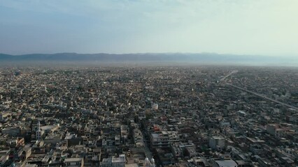 Aerial Flyover Shot of dense population around Muree road Rawalpindi City In Pakistan with mountains of Islamabad in vicinity.  Twin Cities of Pakistan.