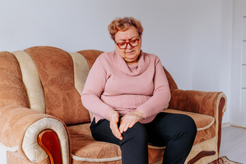 The Struggle of an Overweight Woman Coping with Leg Pain at Home, An elderly woman grimacing in...