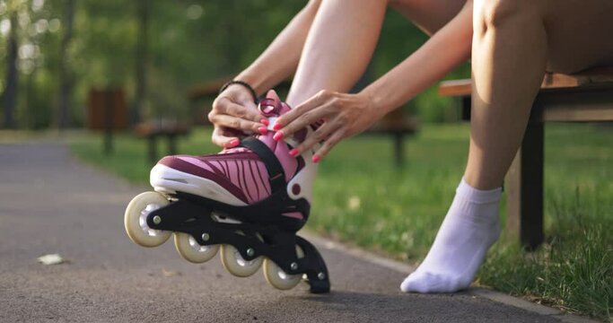 Girl carefully fastens rollerblade on her foot