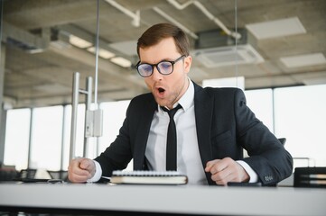 Angry senior businessman sitting at his desk and screaming