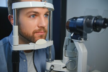 Handsome young man is checking the eye vision in modern ophthalmology clinic. Patient in ophthalmology clinic