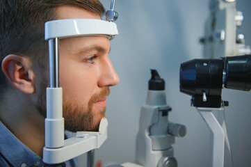 Adult man eyesight test with binocular slit-lamp. Checking retina of a male eye close-up....