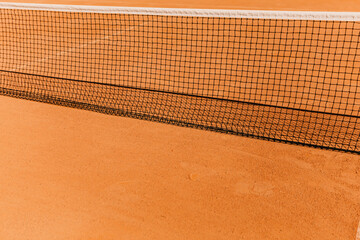 Light orange empty outdoor clay court surface dry grungy ground baseline detail for playing tennis with net in sunny day, gravel texture background, copy space for text inscription banner

 - obrazy, fototapety, plakaty
