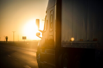 Long Haul 18 Wheel Truck driving on a highway at sunrise or sunset