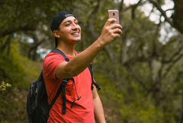 young man takes a selfie while hiking in garland ranch regional park, california, dressed in red with a cap. 