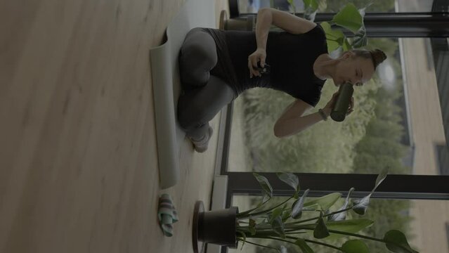 Caucasian woman is drinking water after workout.
