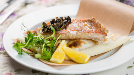 fried pike perch with boiled potatoes on a white plate
