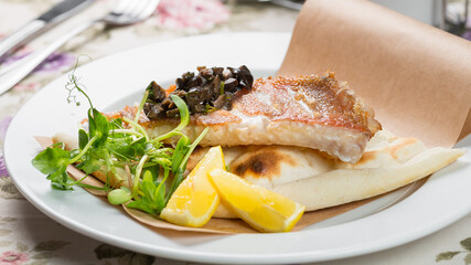 fried pike perch with boiled potatoes on a white plate