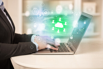 Hands working on laptop with digital icons