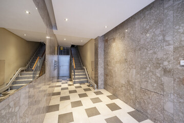 Portal of an urban residential housing building with marble walls, a large mirror integrated into...