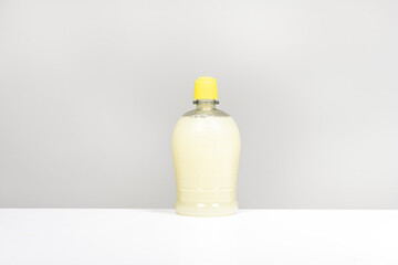 A semi-transparent plastic bottle filled with lemon juice on a smooth white surface