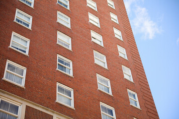 historic brick building structure with glass windows of urban apartment building old residential construction in boston downtown street with blue sky and business concept symbolizing monotonous work
