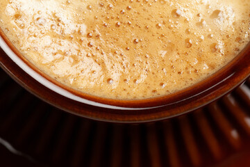 macro of espresso coffee foam in a brown cup, top view, fresh foam, background