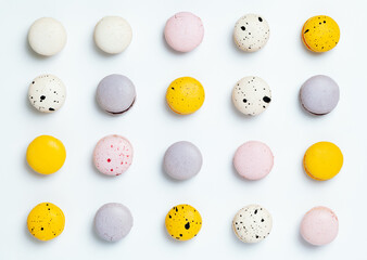 even rows of macarons, multi-colored macaron cookies with specks on a light background, top view