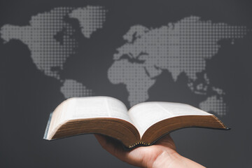Hand holding Holy Bible and world map in blur background. World mission christian idea. Copy space for text. Christian background for great commission or earth day concept. - obrazy, fototapety, plakaty