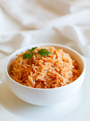 Tomato onion rice, Tamatar Biryani, jollof in white bowl on a white wooden table, vertical