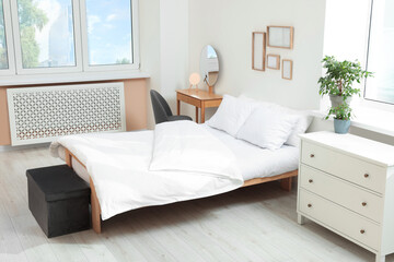 Bed with soft white pillows in cozy room interior