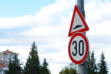 Post with road signs Maximum Speed 30 and Speed Bump outdoors on sunny day, space for text