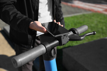 Man using smartphone to pay and unblock rental electric scooter outdoors, closeup