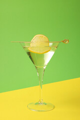 Martini glass of refreshing cocktail with lemon slice on color background