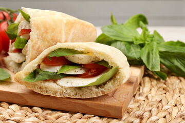 Delicious pita sandwiches with mozzarella, tomatoes and basil on wicker mat