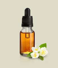 Bottle of jasmine essential oil and flowers on light background