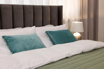 Comfortable bed with bedding and lamp in room