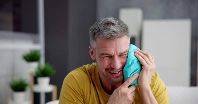 Upset Man Touching Cheek With Cold Water Bag