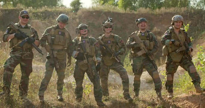 Happy smiling men and woman in camouflage chatting after successful game of war Father's day,slow motion soldiers hugging embracing posing to camera friendship team togetherness