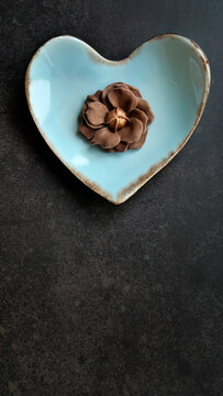 Chocolate flavor, Brown color, Sam Pan Nee traditional Thai handcraft snack on pastel blue heart shape plate, Dark background, vertical image with copy space