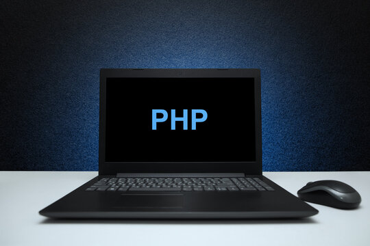 PHP text on laptop screen on textured black background with blue light. Learn php programming language, computer courses, training.
