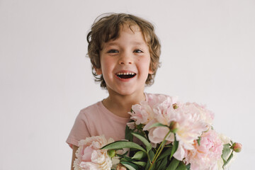 Cheerful happy child with Peonys bouquet. Smiling little boy on white background. Mother's Day....
