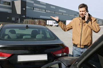 Man talking on phone near car with scratch outdoors Auto accident